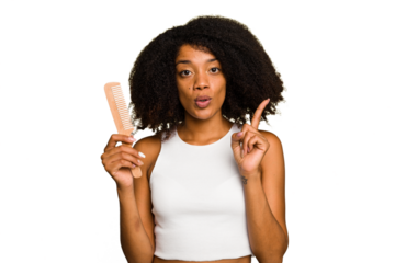 Young african american woman holding hair comb isolated having some great idea, concept of creativity.