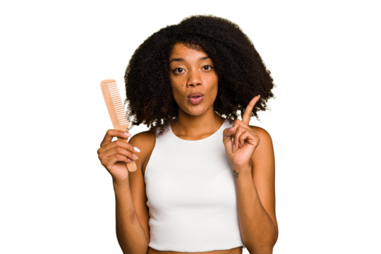 Young african american woman holding hair comb isolated having some great idea, concept of creativity.