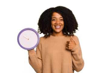 Young African American holding a clock isolated smiling and raising thumb up
