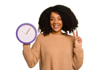 Young African American holding a clock isolated showing number two with fingers.
