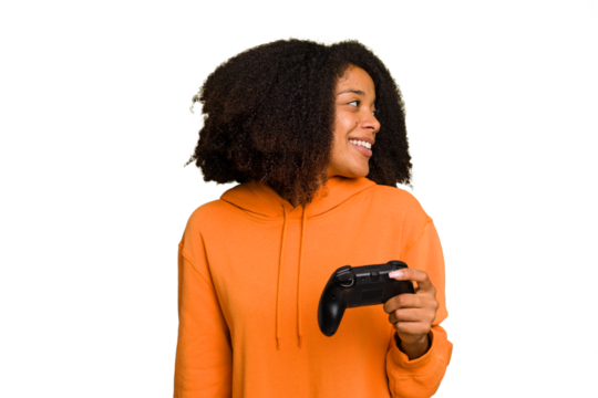 Young African American woman holding a game controller isolated looks aside smiling, cheerful and pleasant.