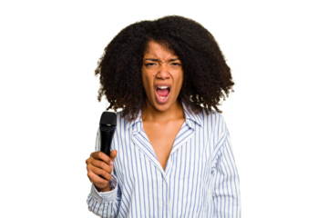 Young African American singer woman holding a microphone isolated screaming very angry and aggressive.