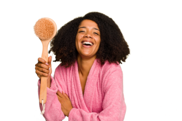 Young African American woman holding a shower brush isolated laughing and having fun.