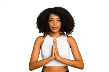 Young African American woman isolated praying, showing devotion, religious person looking for divine inspiration.