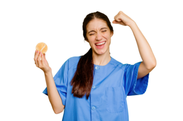 Young caucasian physiotherapist woman holding a tennis ball isolated raising fist after a victory, winner concept.