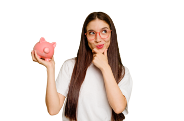 Young caucasian woman holding a piggy bank isolated looking sideways with doubtful and skeptical expression.