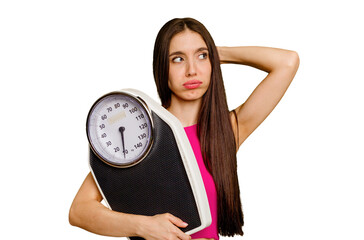 Young caucasian woman holding a scale isolated touching back of head, thinking and making a choice.