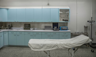 Large room in a medical clinic with examining table, cupboards with supplies and equipment, nobody