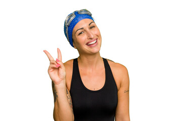 Fototapeta na wymiar Young caucasian swimmer woman isolated on green chroma background joyful and carefree showing a peace symbol with fingers.
