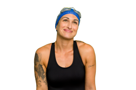 Young caucasian swimmer woman isolated on green chroma background dreaming of achieving goals and purposes