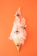 White spider web with black spiders and ice cream cone on orange background. Minimal Halooween...