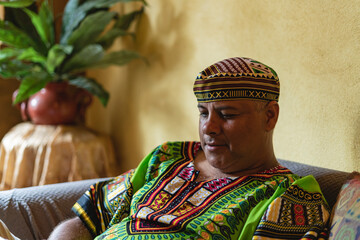 Obraz premium Imagen horizontal de cerca de un hombre adulto latino en el interior de su casa utilizando una camisa y gorro caribeño. 