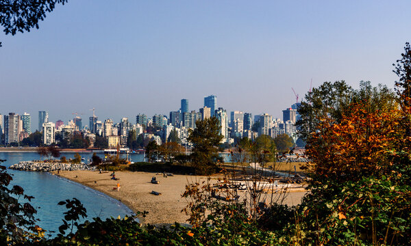 Off-leash area of Kitsilano beach, BC, with buildings of downtown Vancouver in background, against a smoke-hazed sky.