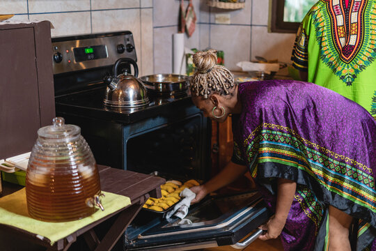 Horizontal de una mujer afrocaribe&ntilde;a en el interior de su cocina sacando del horno unos bocadillos caribe&ntilde;os que acaba de preparar. 