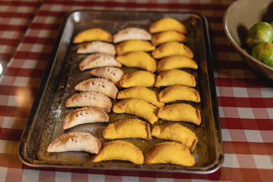 Imagen horizontal de unas deliciosas empanadas al estilo caribe&ntilde;o en una bandeja sobre una mesa en el interior de una casa.