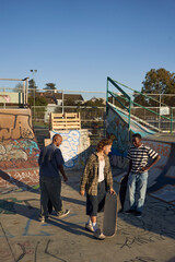 Three young skateboarders in skatepark skateboarding
