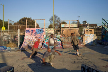 Four young skateboarders in skatepark skateboarding
