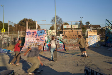 Four young skateboarders in skatepark skateboarding
