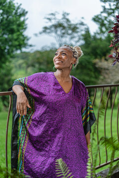 Retrato vertical de una hermosa mujer afrocaribe&ntilde;a muy sonriente en el exterior de su casa disfrutando de un d&iacute;a de verano.