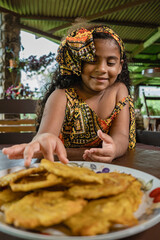 Imagen vertical de una hermosa niña afrocaribeña muy sonriente disfrutando de unos deliciosos...