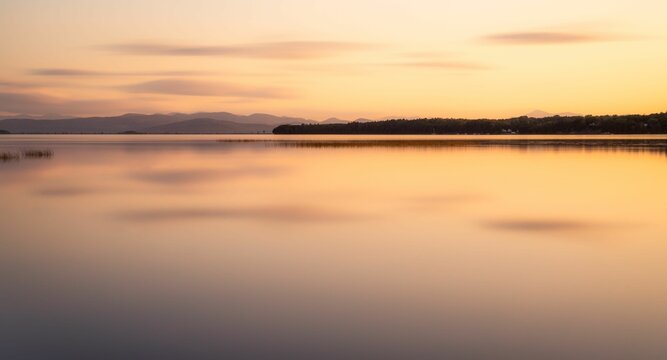 View of a beige sunset sky reflecting on the Lake Champlain