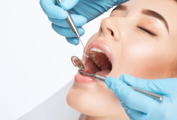 A dentist doctor treats caries on a tooth of a young beautiful woman in a dental clinic. Tooth...