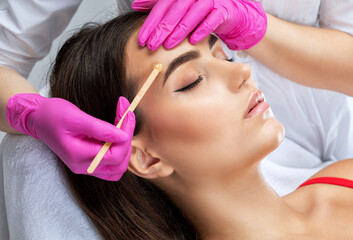 Makeup artist does facial hair removal procedure. Beautiful girl having Permanent Make-up on her...