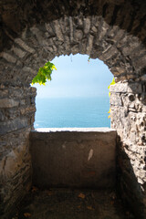window with background of blue sea and water in lake with window of medieval stones and autumn nature