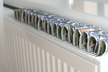 Energy crisis, concept. Savings in the heating season. American dollars on the radiator. Close-up. Soft focus.