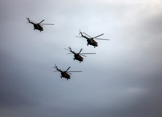 Fototapeta na wymiar Silhouettes of khaki helicopters with red stars on background of cloudy gray clouds.