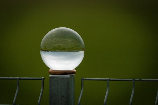 Closeup of a perfect sphere crystal on a metal post and reflecting the surroundings inversely