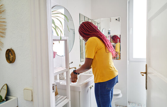 young african american woman washing hands in bathroom at home