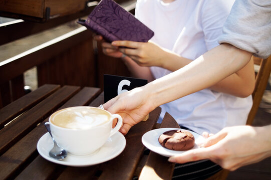 A teenager with blue hair in a cafe is waiting for an order