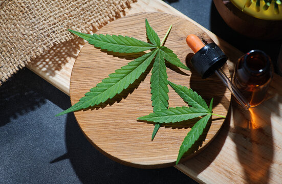The cannabis leaves with dropper on the wooden plate