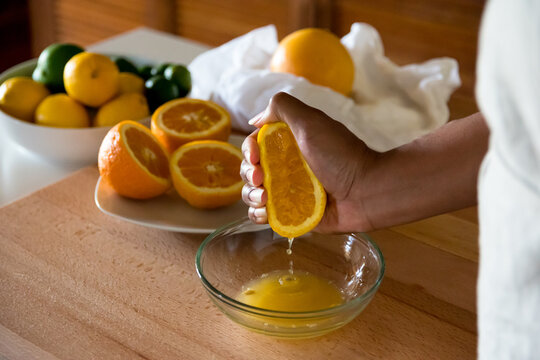 Black woman, African American woman hand squeezing fresh orange juice into glass bowl