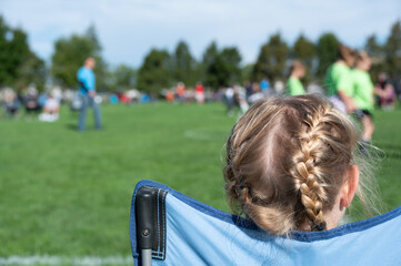 Naklejka premium Younger sister watching a soccer game to support her sibling. 