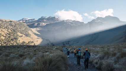 Fototapeta premium Group of hikers walking in grassland with mountains in the background. Iztaccihuatl