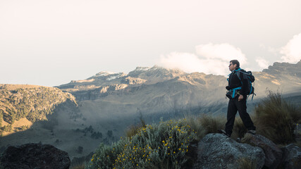 Fototapeta premium Hiker man on a rock, with a mountain in the background