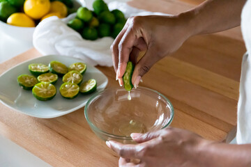 Black woman, African American woman hand squeezing fresh shikuwasa Okinawa lime juice into glass bowl