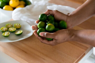 African American woman, Black woman hands cradling, holding a bunch of shikuwasa Okinawa limes