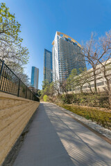 Paved walkway along a wall with railing with view of buildings against blue sky