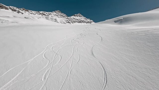 Aerial view empty winter mountain slope with ski snowboard snow trace frozen field extreme sport activity. FPV sports drone shot smooth ride route wild freeride downhill natural cliff ridge landscape