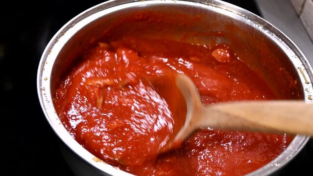 cooking tomato sauce for pasta with wooden ladle real time