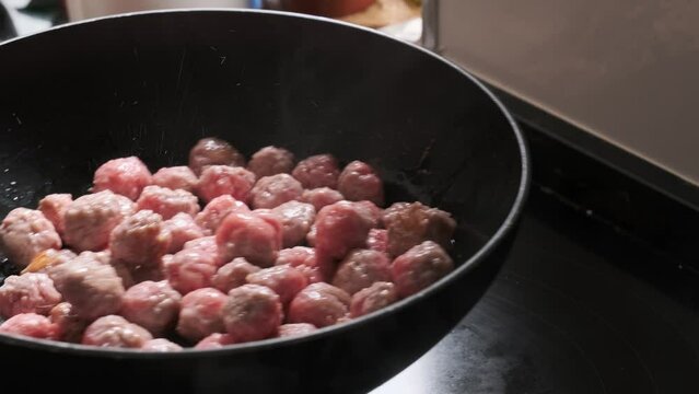 tossing meat balls in a frying pan