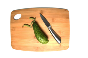 cucumber and a knife on wooden cutting board isolated on white background flat lay