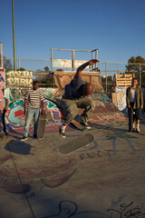 Three young skateboarders in skatepark skateboarding
