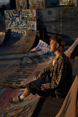 Portrait of young non-binary sitting with skateboard at skatepark
