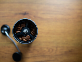 Coffee hand grinder steel and bean coffee inside show top view ready to grind, on table wood backgroud..