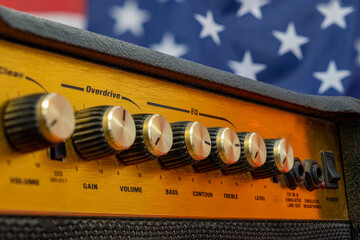 Close-up of the button panel of a guitar or bass amplifier with the American flag in the background.
