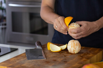 Chef cook cutting fresh orange for fruit salad on wooden cut board